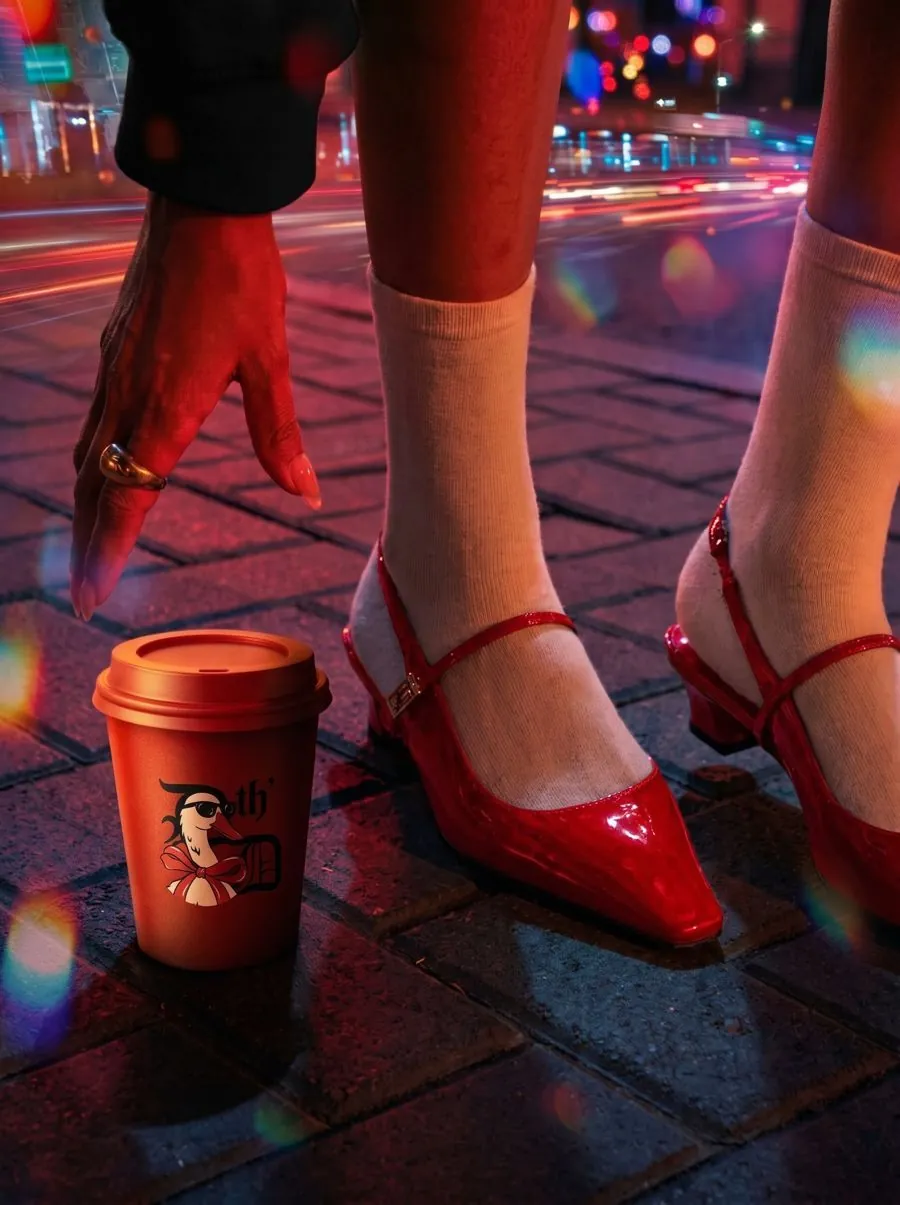 person drinking from a Drink th' Drink cup on a city street